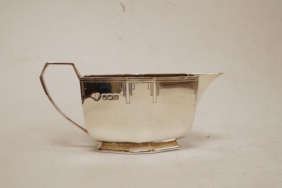 A George VI Art Deco silver five piece tea service with a matching two handled tea tray, by Hamilton & Co, of octagonal form, with engraved decoration, Sheffield, 1937/38 lacking handles and knops, tray 53.4cm, over hand